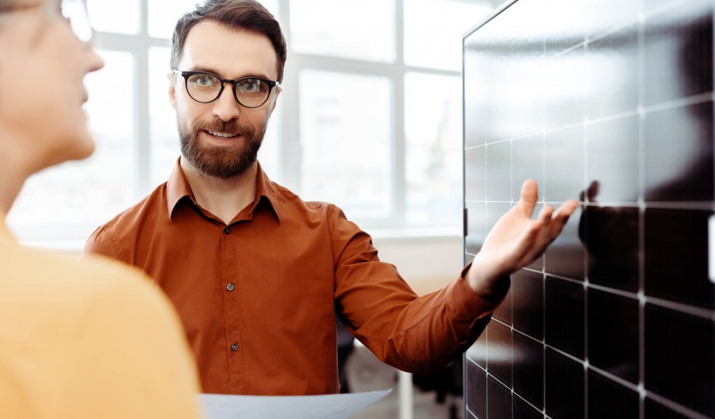 Business people, engineers working with solar panel in modern office. Smiling confident colleagues talking, cooperation, explaining something, planning startup. Teamwork, successful business concept
